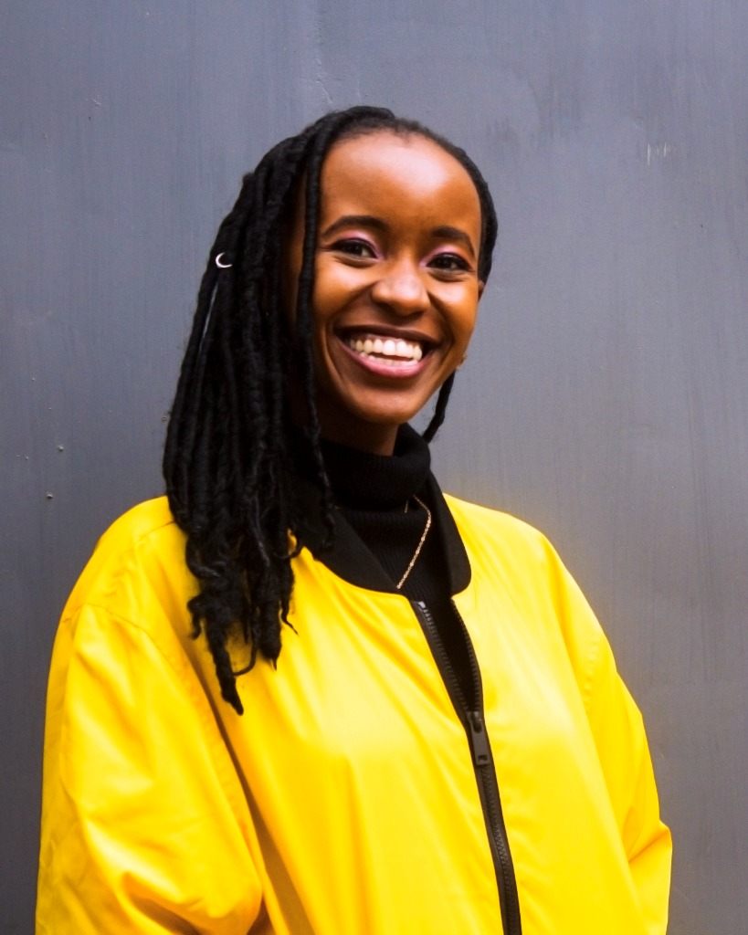 Joy Kathambi smiling in a yellow jacket